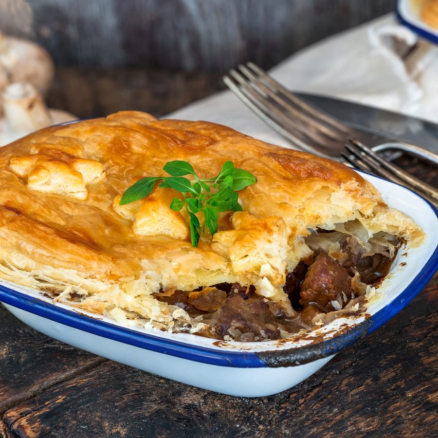 A steak and mushroom pie served in a blue and white enamel pie tin